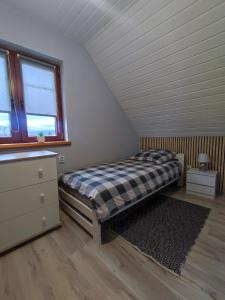 ein Schlafzimmer mit einem Bett, einer Kommode und einem Fenster in der Unterkunft Domki w Bieszczadach Nova Dolina in Średnia Wieś