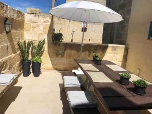 a wooden table with an umbrella on a patio at Daner Ta’ Pantu House in Kerċem