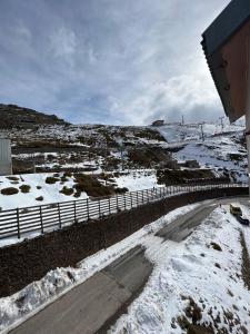 una carretera nevada con una valla junto a un campo nevado en SAINT MORITZ CON VISTAS, en Sierra Nevada