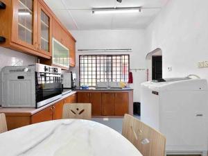 uma cozinha com uma mesa e um frigorífico branco em TAMAN UNIVERSITI THREE BEDROOMS 6-10Pax UTM, SKUDAI em Skudai