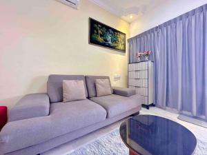 TAMAN UNIVERSITI THREE BEDROOMS 6-10Pax UTM, SKUDAI في سكوداي: غرفة معيشة مع أريكة وطاولة زجاجية