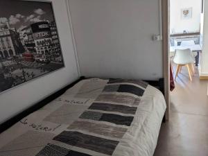 uma cama num quarto com uma fotografia na parede em Appartement 4 voyageurs - Proche plage em Bray-Dunes