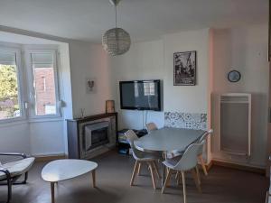uma sala de estar com uma mesa e cadeiras e uma televisão em Appartement 4 voyageurs - Proche plage em Bray-Dunes