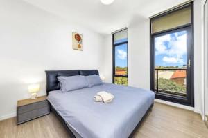 een slaapkamer met een groot bed en een groot raam bij comfy 2B apartment in Zetland in Sydney