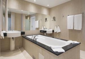 a bathroom with a large tub and two sinks at Thon Hotel Opera in Oslo