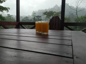 um copo de sumo de laranja sentado numa mesa de madeira em Sinharaja Forest Gate em Deniyaya