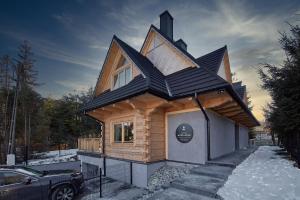 a small house with a black roof in the snow at Tatra Wood House Boutique in Zakopane