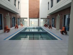 uma piscina no meio de um edifício com cadeiras em Al Salam Resort em Al Khiran