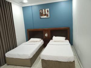 two beds in a room with a blue wall at Al Salam Resort in Al Khīrān