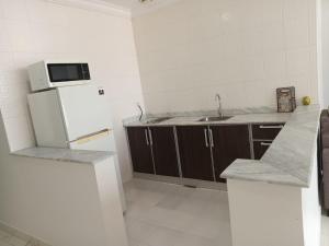 a kitchen with a white refrigerator and a sink at Al Salam Resort in Al Khīrān