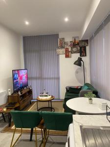 uma sala de estar com cadeiras verdes e uma televisão em Home away from home em Brierley Hill