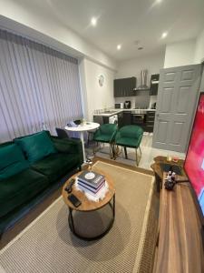 uma sala de estar com um sofá verde e uma mesa em Home away from home em Brierley Hill