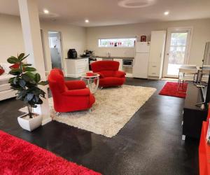 uma sala de estar com duas cadeiras vermelhas e uma cozinha em Whispering Woods Amore em Maryborough