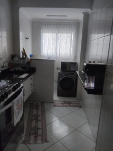 a dirty kitchen with a washing machine in it at Ap 1 dormitório Praia Grande(canto do forte) 100m da praia in Praia Grande