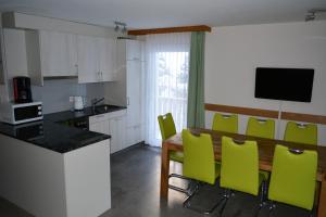 a kitchen with a wooden table and green chairs at Haus Amasaas in Saas-Fee