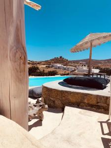 a swimming pool and an umbrella next to a swimming pool at My Oasis Studios Mykonos in Klouvas