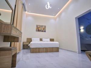 a white bedroom with a bed and a staircase at شاليهات لاڤيرا in Hafr Al Baten