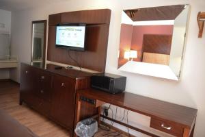 a room with a desk with a television and a mirror at Relax Inn in Collinsville