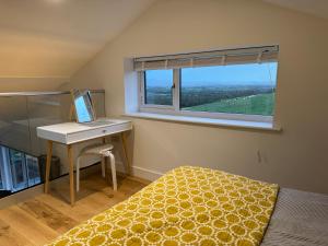 a bedroom with a bed and a desk with a laptop at The Lookout in Wedmore