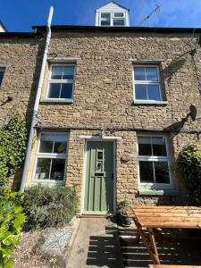 a brick house with a green door and a bench at Cosy two bed townhouse in Centre of C.Norton in Chipping Norton