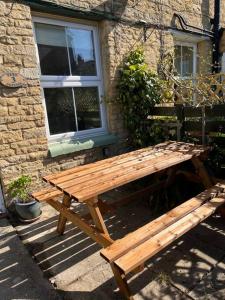 a wooden picnic table in front of a building at Cosy two bed townhouse in Centre of C.Norton in Chipping Norton