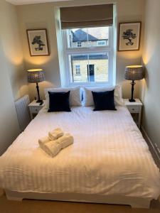 a bedroom with a large white bed with two lamps at Cosy two bed townhouse in Centre of C.Norton in Chipping Norton