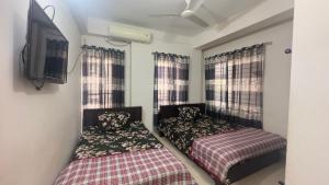 sypialnia z 2 łóżkami i telewizorem z płaskim ekranem w obiekcie Appayan Guest House (Baridhara) w mieście Dhaka