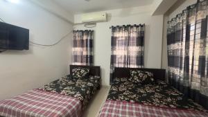 two beds in a small room with windows at Appayan Guest House (Baridhara) in Dhaka