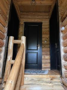 uma porta preta de um chalé de madeira com um alpendre de madeira em AirGreen Cabană 