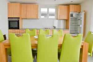 uma cozinha com uma mesa de madeira e cadeiras verdes em Heidi em Saas-Fee