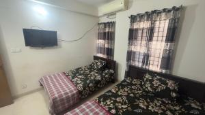 um quarto com uma cama e uma televisão de ecrã plano em Appayan Guest House (Baridhara) em Daca