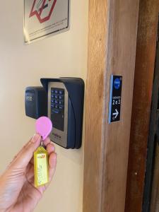 a person holding a pink bottle in front of a door at Hostel 364 Santos Dorm Privativo com Alexa in Santos