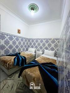 two beds in a room with blue and white wallpaper at Hotel Dar Youssef 1 in Marrakech
