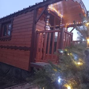 a cabin with christmas lights on the porch at L'encantada- Roulotte in Rieux