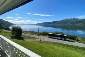 un autobús conduciendo por una carretera junto a un lago en Skogstad Ferie og fritid en Tromsø