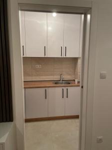 - une cuisine avec des placards blancs et un évier dans l'établissement Apartman Jovanov Dvor, à Bijeljina