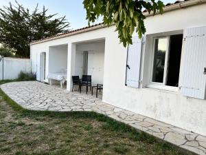 a white house with a patio and a table at Maison lumineuse à Ars en ré in Ars-en-Ré