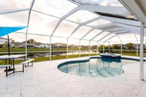 einen Pool mit einem Pavillon mit einem Tisch und Bänken in der Unterkunft Cheerful 4 Bedroom Salt Water Heated Pool & Spa in Riverview