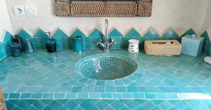 Łazienka z umywalką i niebieską podłogą wyłożoną kafelkami w obiekcie La Maison d'Hélène Essaouira w mieście Oulad el Madani