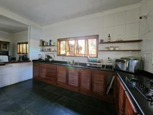 a large kitchen with wooden cabinets and a window at Casa de Férias Casa Mia in Santa Cruz Cabrália