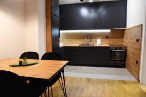 a kitchen with black cabinets and a wooden table at Apartman Besta in Banja Luka