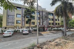 a building with two cars parked in a parking lot at Hotel Flysky Rooms & Banquets in Navi Mumbai