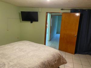 1 dormitorio con 1 cama y TV en la pared en Departamento céntrico casa Paulora, en Hidalgo del Parral