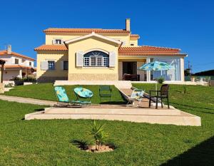 two chairs and an umbrella in front of a house at Casa Harmonica com vista mar in Areia Branca