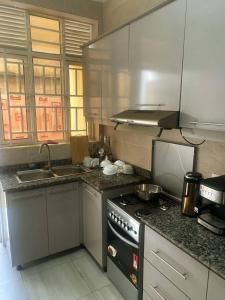 cocina con fogones y fregadero. en ADRIEL HOMES KIGALi en Kigali