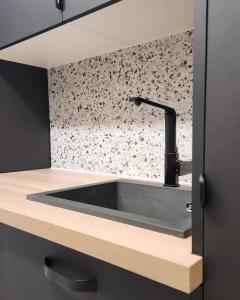 a sink in a kitchen with a black wall at Gîte de groupe "La Donaclaudré" pour vos événements en pleine nature - 15 à 120 personnes proche de Disneyland Paris in Saint-Augustin