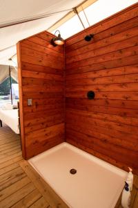 a bath tub in a room with a wooden wall at Off Map Glamping in South Haven