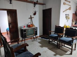 a living room with chairs and a tv and a cross on the wall at El Caña Bravo Posada, Alojamiento de Descanso in Duitama