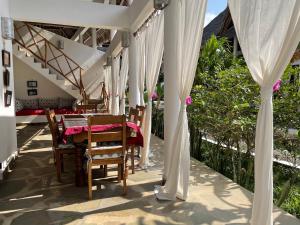 a table and chairs on a patio with white curtains at Paka House-Rafiki Village in Watamu