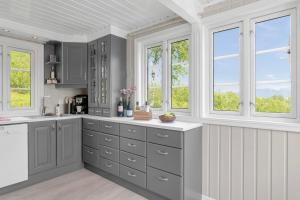 una cocina con armarios grises y ventanas en Centrally Located Cabin by the Sea - Sortland, en Sortland